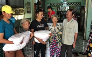 Võ Hoàng Lâm (giữa) đang phát gạo cho bà con nghèo