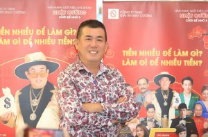 Danh hài Nhật Cường với Poster phía sau có các gương mặt trong phim Nhà Bà Nữ: Việt Anh, Trấn Thành, Lê Giang