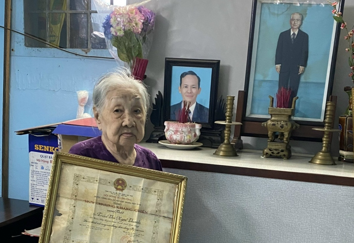 Cụ Trần Thị Ngọc Thanh cùng Huy chương Kháng chiến hạng Nhất trước bàn thờ cụ Bùi Hữu Ngự và con trai Bùi Hữu Đức